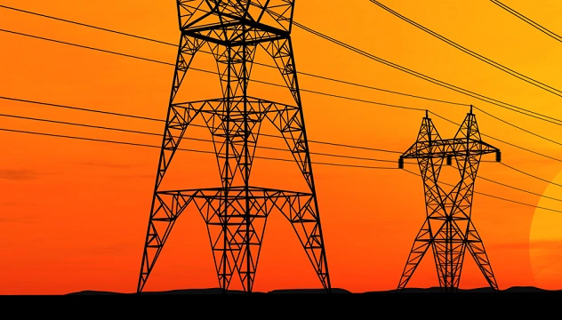 A bright yellow and orange sunset behind silhouettes of electronic transmission towers.
