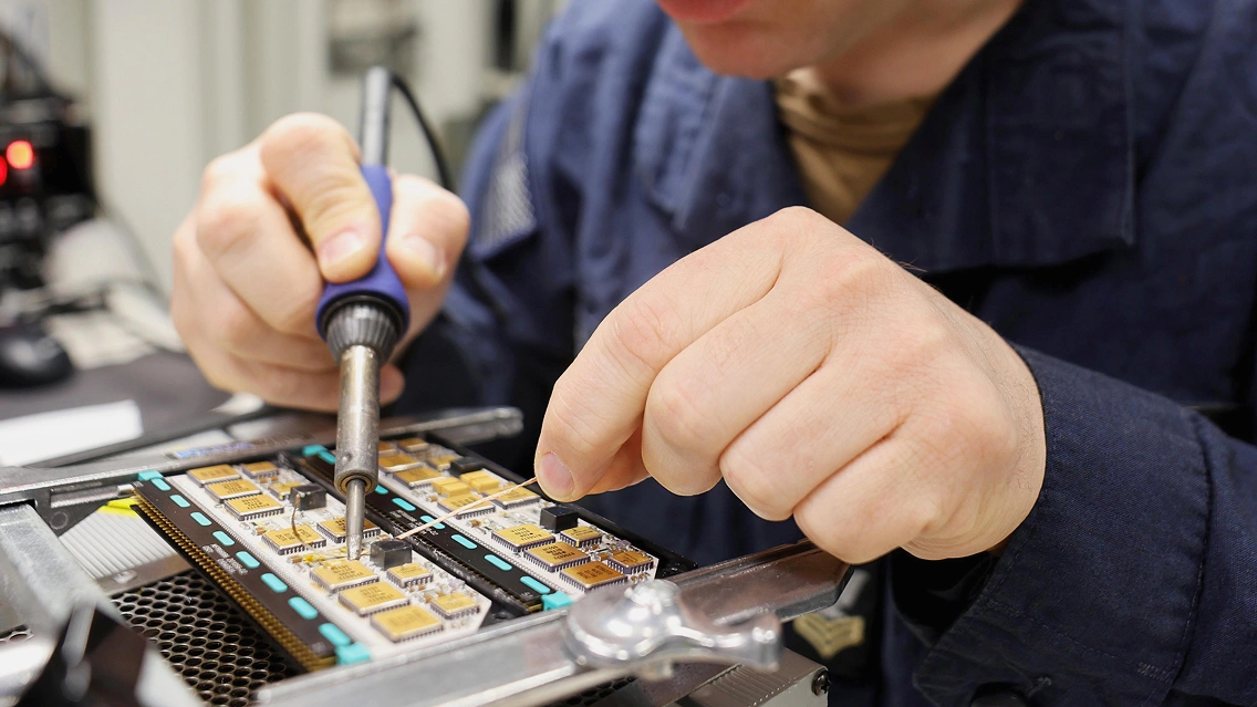 Close-up of a technician soldering components onto a circuit board.