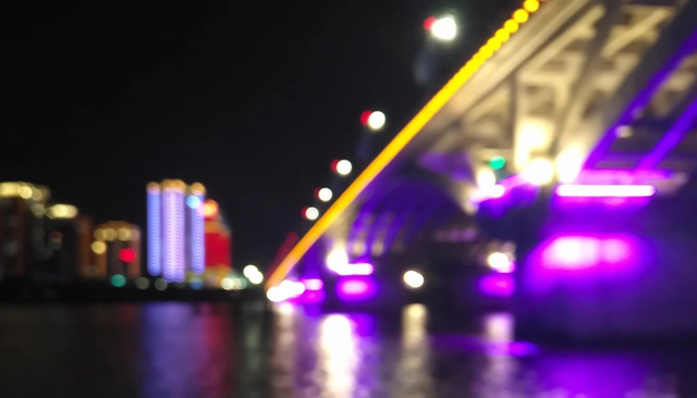 A river-spanning bridge at night lit in purple.