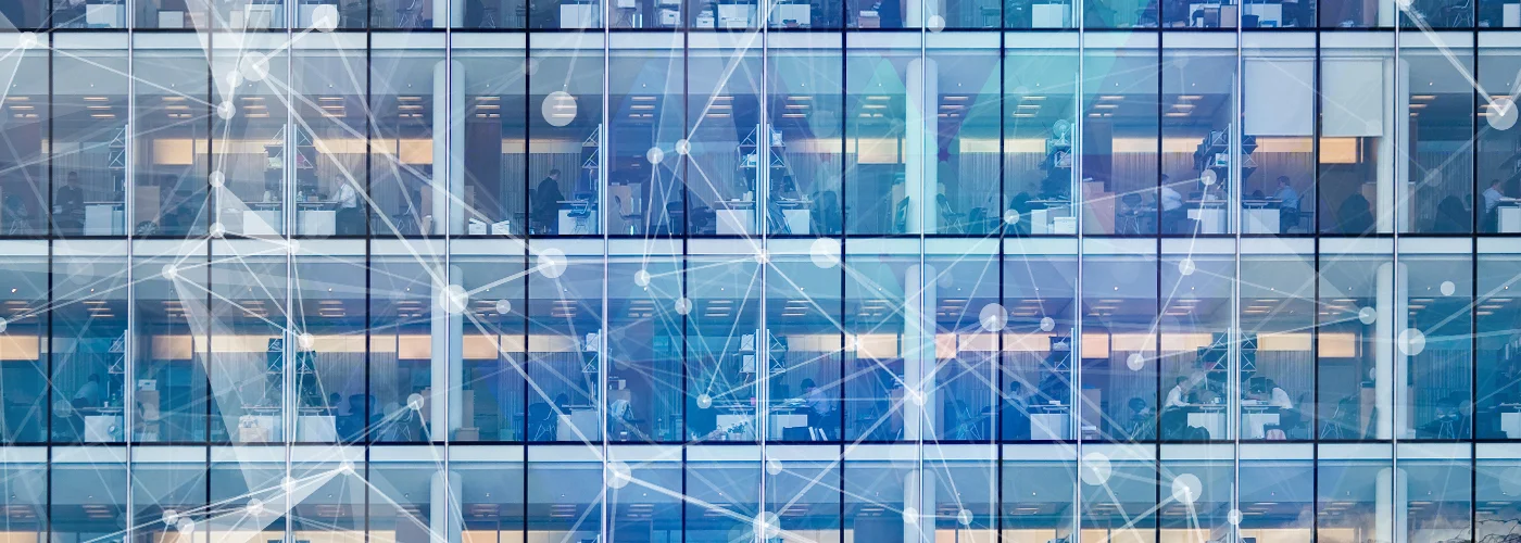 Photo illustration of the exterior of an office building, with large windows showing the offices inside. A series of interconnected nodes overlays the photo.