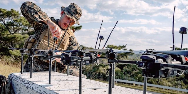 Soldier in uniform assembling drones.