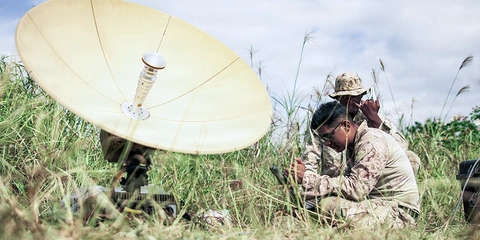 Military personnel setting up equipment a field.