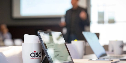 Close-up of a tablet and a CiSO CMU branded mug.