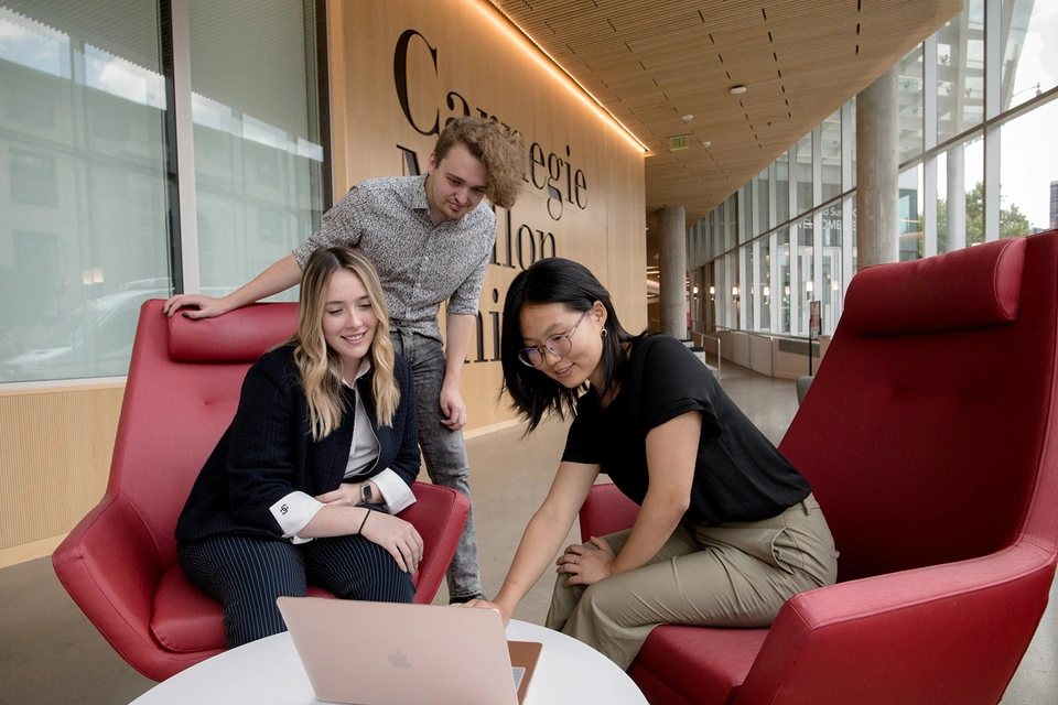 SEI interns collaborating around laptop on the Carnegie Mellon campus.