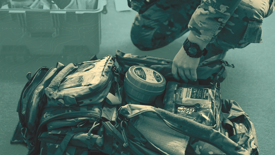 SWA Go Bag. A uniformed person packs a camouflage backpack with expeditionary supplies.
