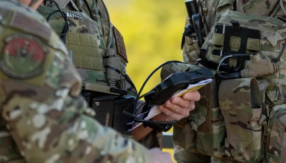Uniformed personnel consult a handheld device